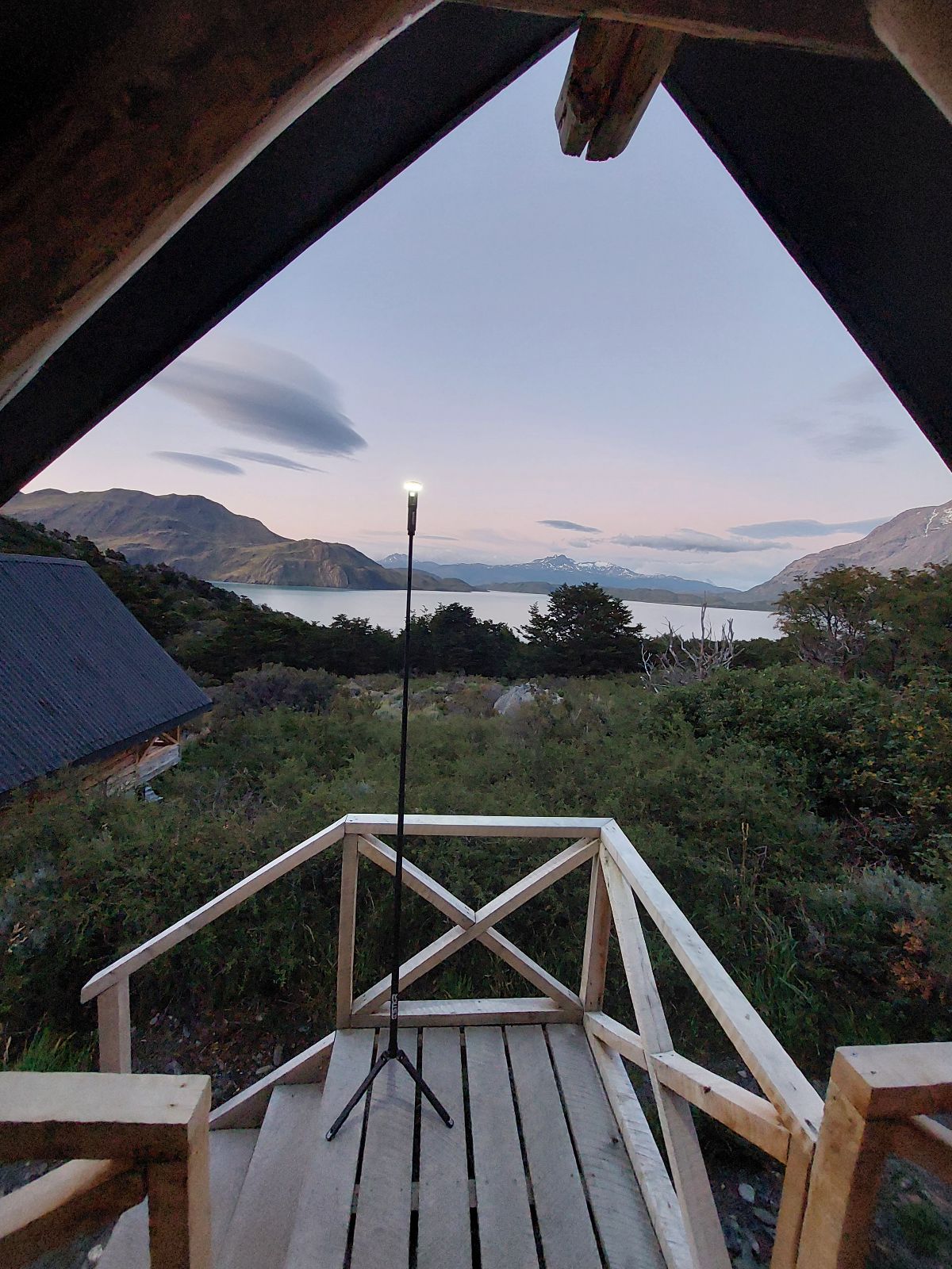 Wooden deck with a view of a lake and mountains at dusk. The small deck is lit up by a FLi-LITE