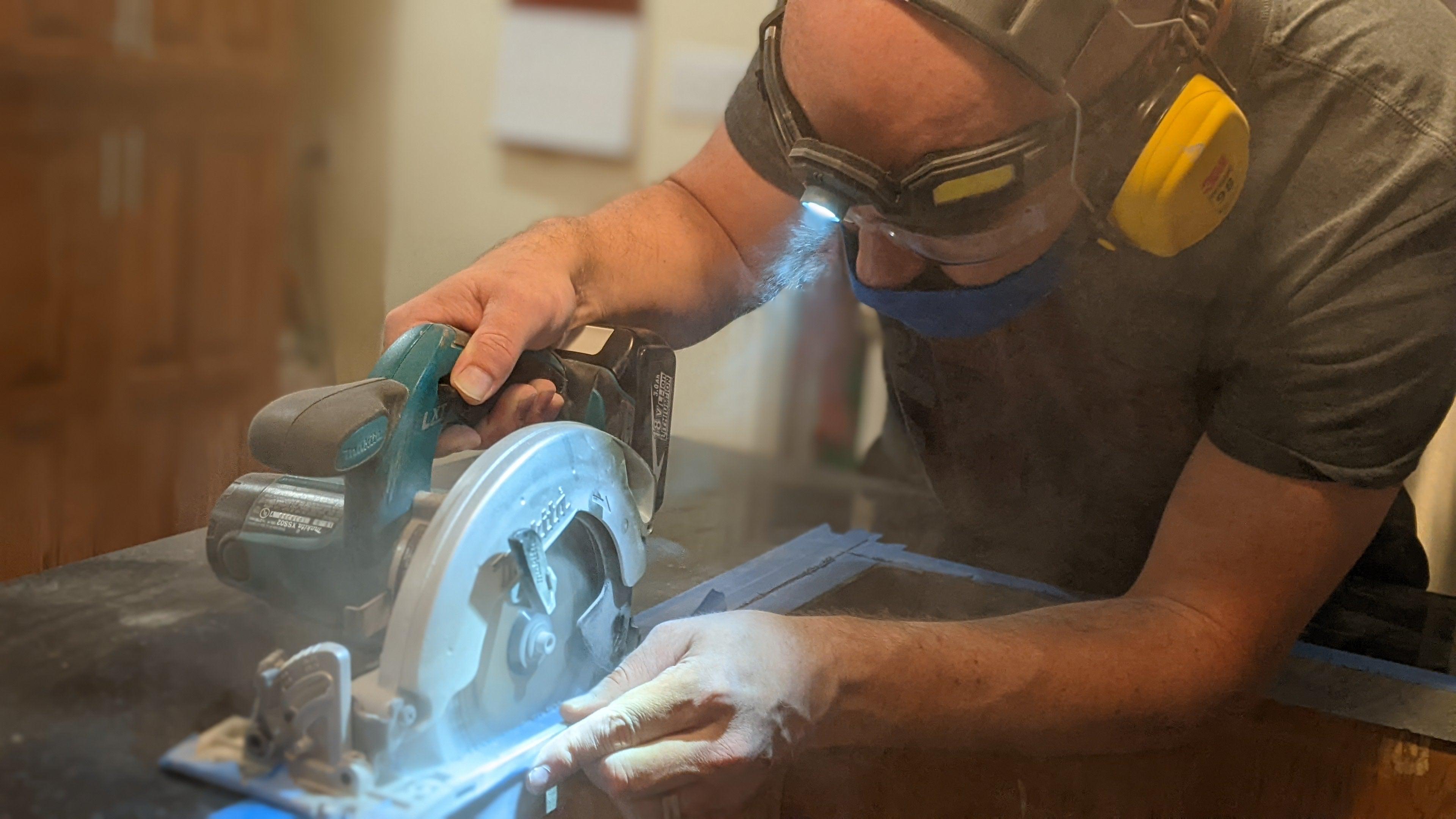 man cutting marble countertop with skill saw using a FLEXIT Headlamp Pro to illuminate his cut